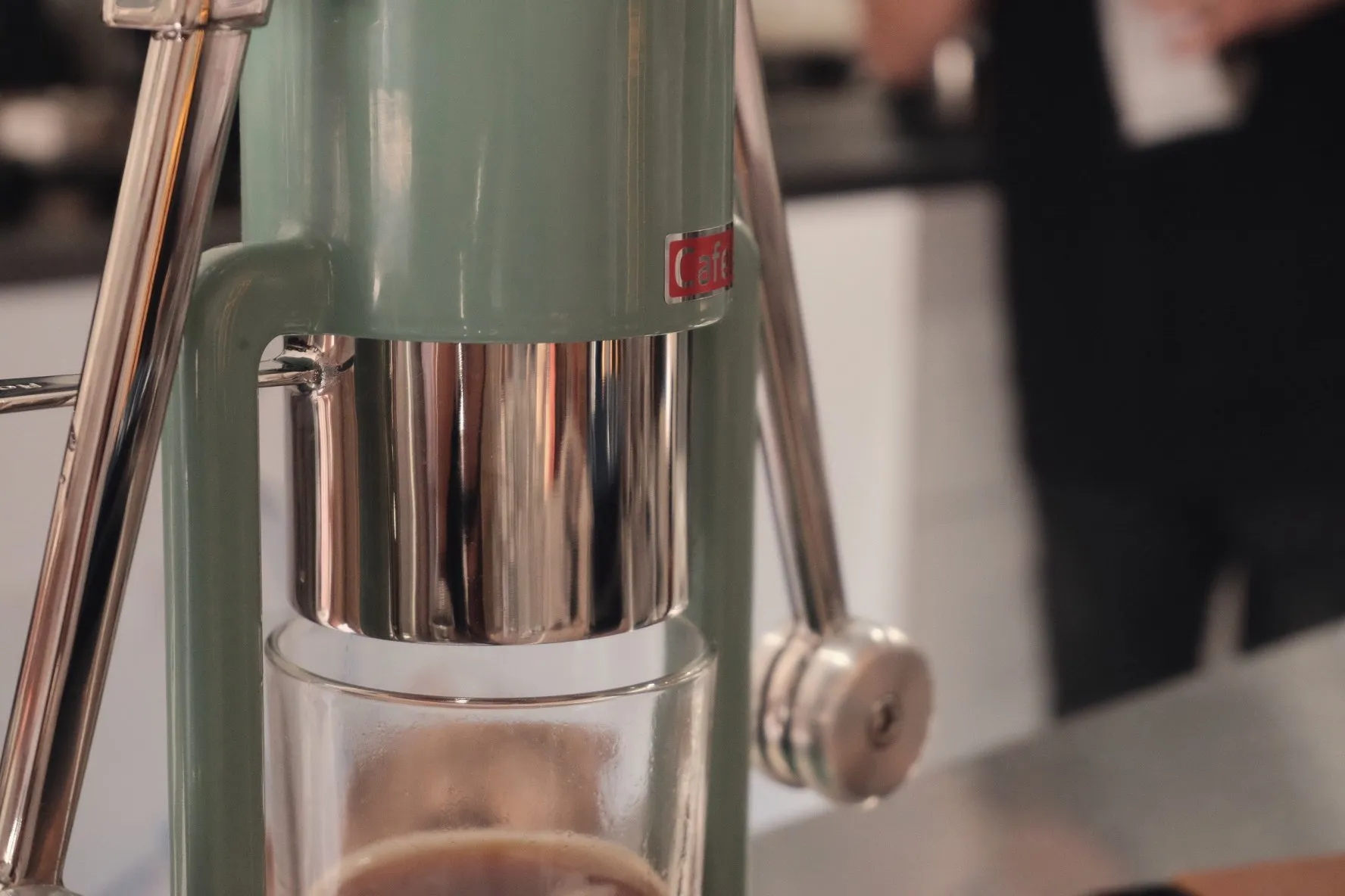Hands pulling the lever on a manual espresso machine