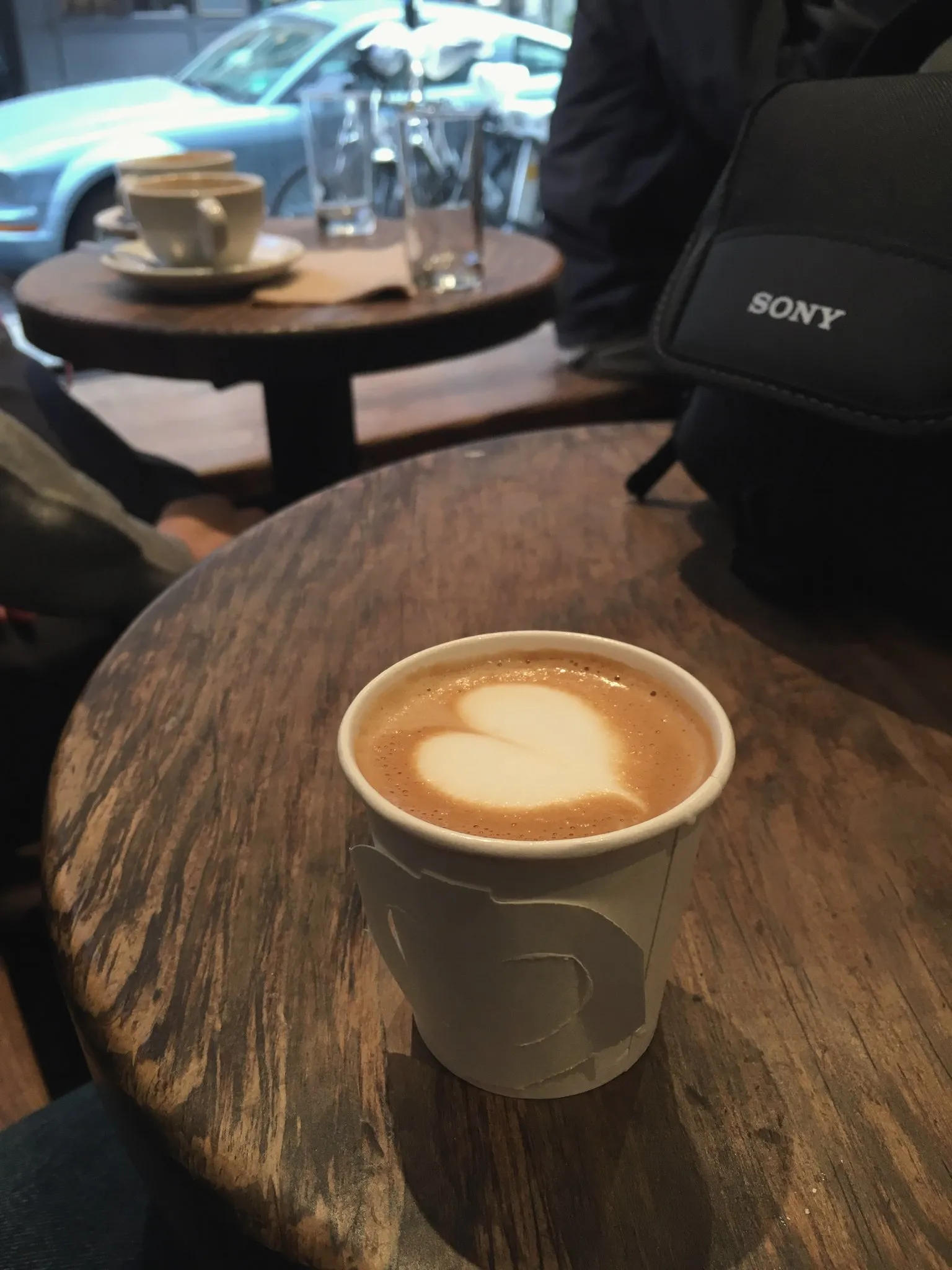 A latte on a round wooden table inside a Manhattan café