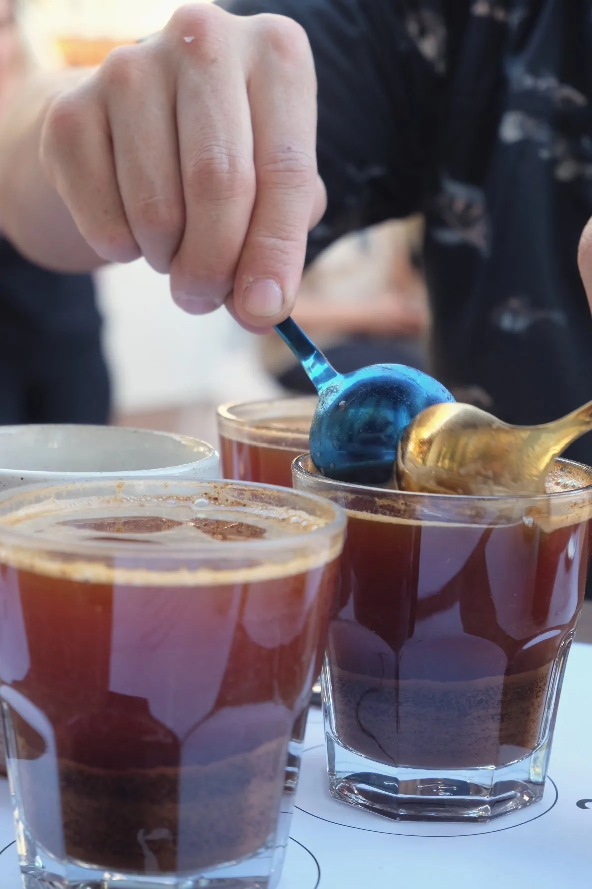 Scooping coffee grounds with a cupping spoon
