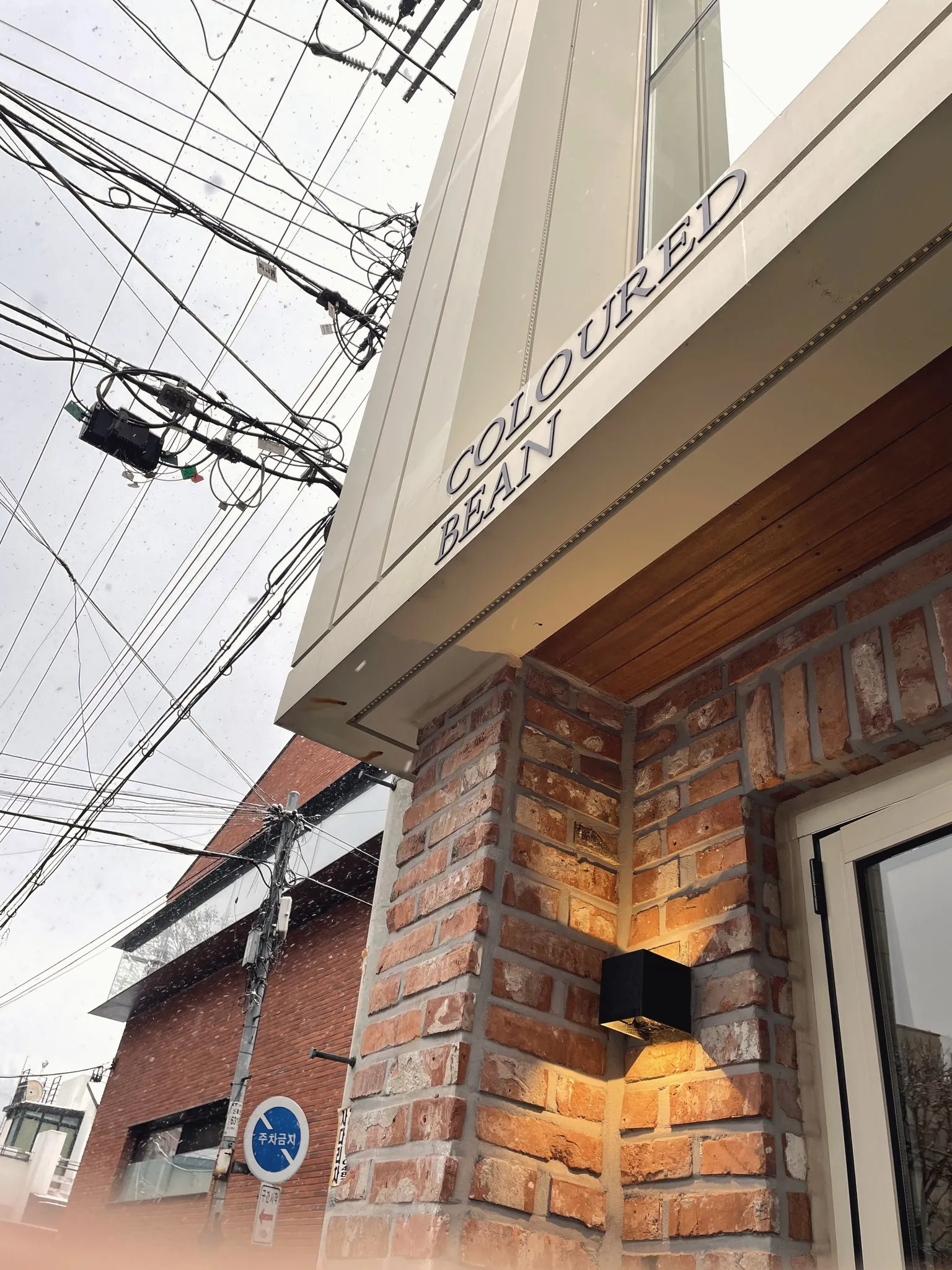 A lit brick cafe exterior on a snowy Seoul evening